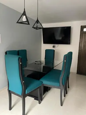 a dining room table with blue chairs and a television at no Reservar in Bello