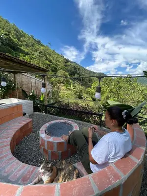 a woman sitting on a brick fireplace next to a cat at Apartamento campestre para pareja en Manizales in Manizales