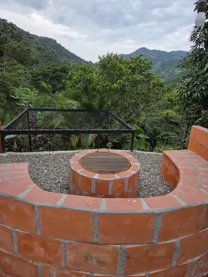 a brick fire pit with a bench and mountains in the background at Apartamento campestre para pareja en Manizales in Manizales