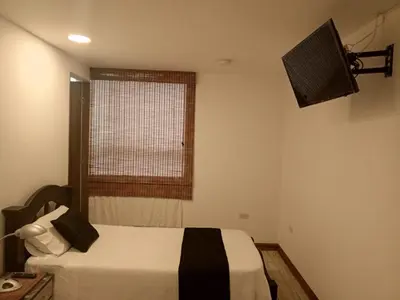 a bedroom with a bed and a window and a television at Hotel Palo Grande in Manizales