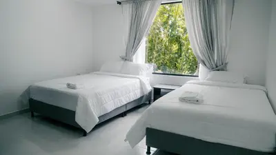 two beds in a room with a window at Finca Hotel Los Alpes in Manizales