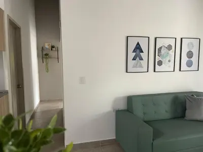 a living room with a green couch and pictures on the wall at Apartamento con vista a laureles 401 in Medellín