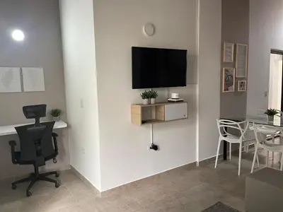 a living room with a chair and a television on a wall at Apartamento con vista a laureles 401 in Medellín