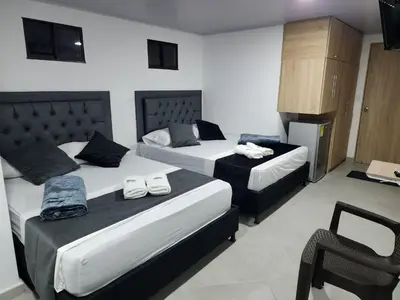 a hotel room with two beds and a chair at Aparta estudios Estadio la 80 in Medellín