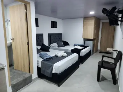 a hotel room with two beds and a chair at Aparta estudios Estadio la 80 in Medellín