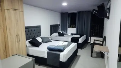a bedroom with two beds and a chair and a couch at Aparta estudios Estadio la 80 in Medellín