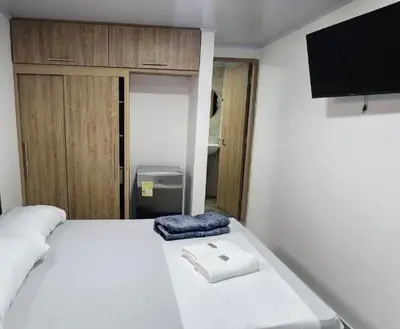 a bedroom with a white bed with a tv on it at Aparta estudios Estadio la 80 in Medellín