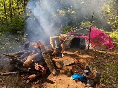 a bonfire with a tent in the woods at Reserva Wanaka, San Carlos in Cocorná
