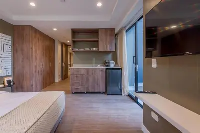 a bedroom with a bed and a kitchen with a counter at El Tesoro Medellín Hab309 by Letoh in Medellín