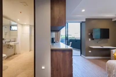 a kitchen with a counter and a living room at El Tesoro Medellín Hab309 by Letoh in Medellín