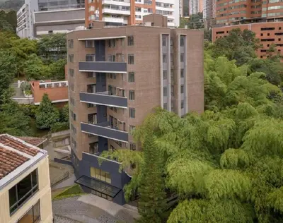 a tall building with trees in front of it at El Tesoro Medellín Hab314 by Letoh in Medellín