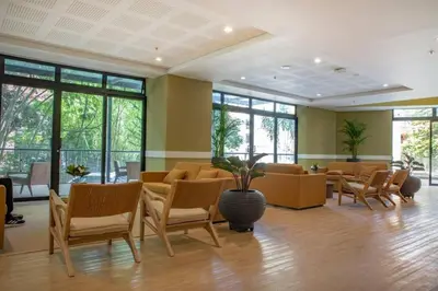 a waiting room with chairs and tables and windows at El Tesoro Medellín Hab314 by Letoh in Medellín