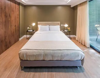 a bedroom with a bed and two tables with lamps at El Tesoro Medellín Hab315 by Letoh in Medellín