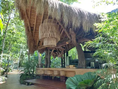 a restaurant with a thatched roof and tables and chairs at Hotel Boutique Maitta en Doradal Antioquia in Doradal