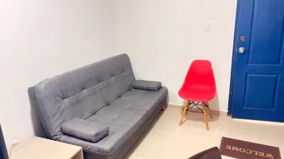 a gray couch in a room with a red chair at Apartaestudio sector la presentacion in Manizales