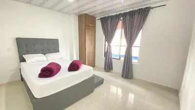 a bedroom with a white bed with two burgundy pillows at Apartamento Balcón 201 in San Luis