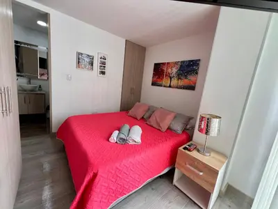 a bedroom with a red bed with a red blanket at Confortable apartaestudio in Manizales