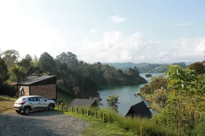 a car parked on a gravel road next to a river at Cabaña con jacuzzi y acceso al embalse - Portum II in El Peñol