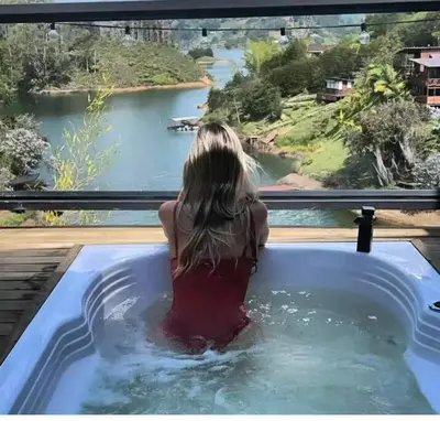 a woman in a hot tub looking out at a river at Cabaña con jacuzzi y acceso al embalse - Portum II in El Peñol