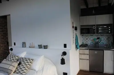 a bedroom with a white bed and a kitchen at Cabaña con jacuzzi y acceso al embalse - Portum II in El Peñol