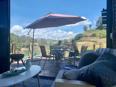 two people sitting at a table under an umbrella at Cabaña con jacuzzi y acceso al embalse - Portum I in El Peñol