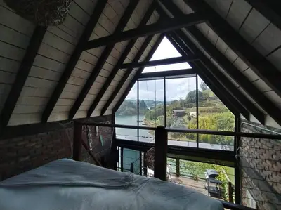 a bedroom with a large window with a view at Cabaña con jacuzzi y acceso al embalse - Portum I in El Peñol