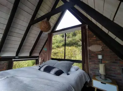 a bed in a room with a window at Cabaña con jacuzzi y acceso al embalse - Portum I in El Peñol