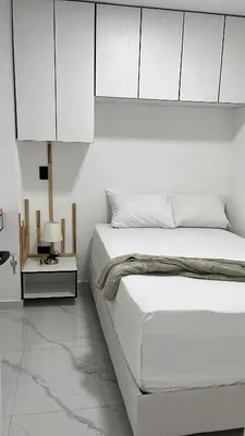 a white bedroom with a bed and a night stand at perla 3 dormitorios in Bello