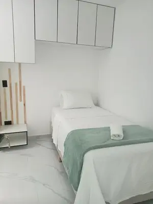 a white bedroom with a bed and white cabinets at perla 3 dormitorios in Bello