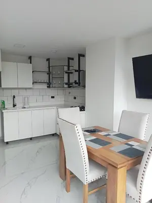 a kitchen with a wooden table and white chairs at perla 3 dormitorios in Bello