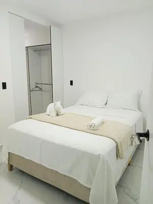 a white bedroom with a large bed and a mirror at perla 3 dormitorios in Bello