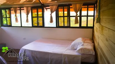 a bedroom with a bed in a room with windows at Chalet Lupe-Eje cafetero in Palestina