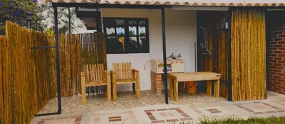 a patio with two wooden chairs and a table at Chalet Lupe-Eje cafetero in Palestina