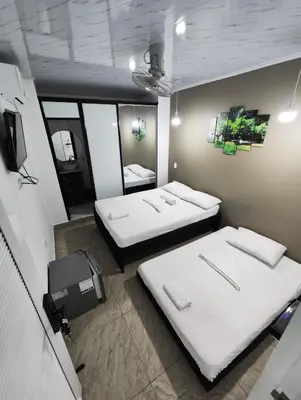a room with two beds and a tv in it at HOSPEDAJE EL ENSUEÑO in Doradal