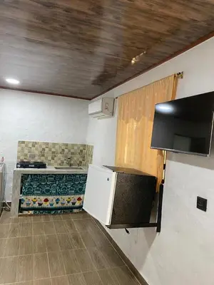 a room with a tv and a kitchen with a refrigerator at Hospedaje Luz d' Luna in Puerto Triunfo
