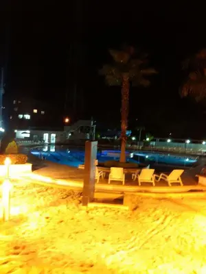 a beach with chairs and a palm tree at night at SANTAFE APARTASOLES in Santa Fe de Antioquia