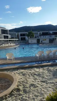 a swimming pool with chairs and people in the water at SANTAFE APARTASOLES in Santa Fe de Antioquia
