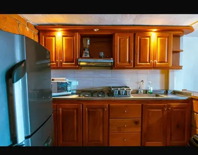 a kitchen with wooden cabinets and a stainless steel refrigerator at Suite Doble in Jericó