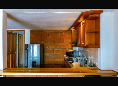 a kitchen with wooden cabinets and a brick wall at Suite Doble in Jericó