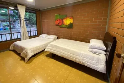 two beds in a room with a brick wall at Casa Vélez in Villamaría