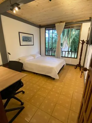 a bedroom with a bed and a desk and window at Casa Vélez in Villamaría