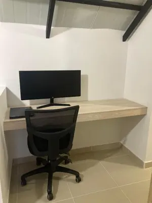 a computer monitor sitting on a desk with a chair at La Casita De Colores in Guatapé
