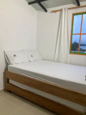 a bed in a white room with a window at La Casita De Colores in Guatapé