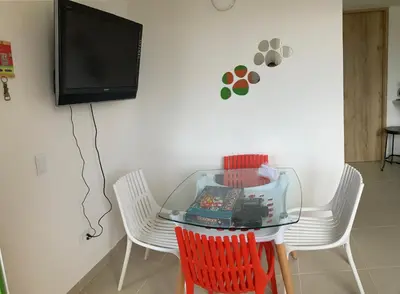 a table with chairs and a tv on a wall at La Casita De Colores in Guatapé
