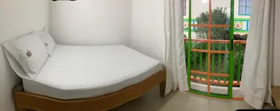 a small bed in a room with a window at La Casita De Colores in Guatapé