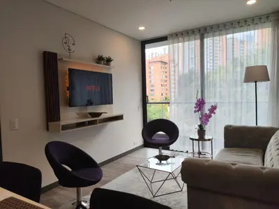 a living room with a couch and chairs and a tv at Tropical Confort suite Poblado in Medellín
