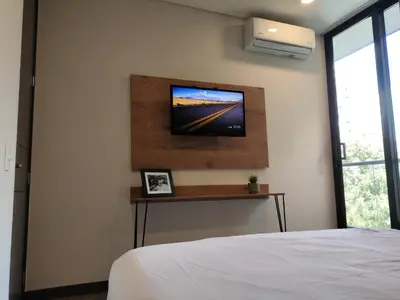 a bedroom with a bed and a tv on the wall at Tropical Confort suite Poblado in Medellín