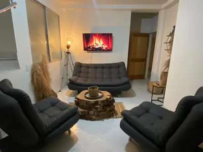 a living room with black couches and a fireplace at Casa Magia in Urrao