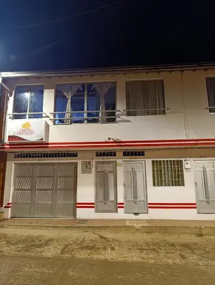 a white house with two garage doors and windows at Casa Magia in Urrao