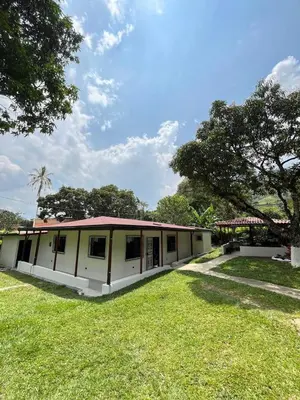 a white building with a red roof on a grass field at Finca Maribet in Cisneros